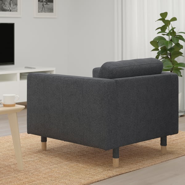 Ein moderner dunkelgrauer Sessel, gepolstert mit weichem Stoff, in der Nähe eines Tisches mit einer Tasse, auf einem geflochtenen Teppich, der Komfort und Stil bietet.