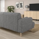 Ein modernes graues LÅNGARYD-Sofa mit Holzbeinen in einem Wohnzimmer. Es ist größer als andere Möbel und bietet ausreichend Sitzgelegenheiten.