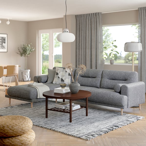 Modernes Wohnzimmer mit grauem LÅNGARYD-Sofa, großem und gemütlichem Couchtisch aus Holz, stilvoller Einrichtung, großem Fenster mit Vorhängen.