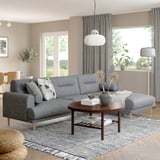 Modernes Wohnzimmer: graues LÅNGARYD-Sektionssofa, weiße Pendelleuchte, Couchtisch aus Holz, großes Fenster, Pflanzen, Teppich, gemütliche Einrichtung.