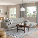 Modernes Wohnzimmer mit grauem LÅNGARYD-Sofa, elegantem Couchtisch, grauem Teppich und Hängelampen. Das Sofa ist groß, bequem, mit weichen runden Formen.