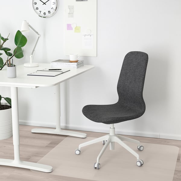 Grauer LÅNGFJÄLL Bürostuhl unter dem Schreibtisch mit Lampe, Pflanzen und Uhr.