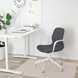 Minimalistisches Homeoffice: Schreibtisch, Uhr, Pflanze, ergonomischer Stuhl.