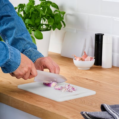 Person schneidet Zwiebel auf einem LEGITIM Kunststoff-Schneidebrett, das einfach zu bedienen und zu reinigen ist.