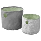 Zwei runde, wendbare Aufbewahrungskörbe, einer grau und einer weiß mit Tupfen, hergestellt aus recyceltem Polyester in Pastellfarben.