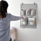 Frau mit grauem Wandorganizer für Babyartikel.