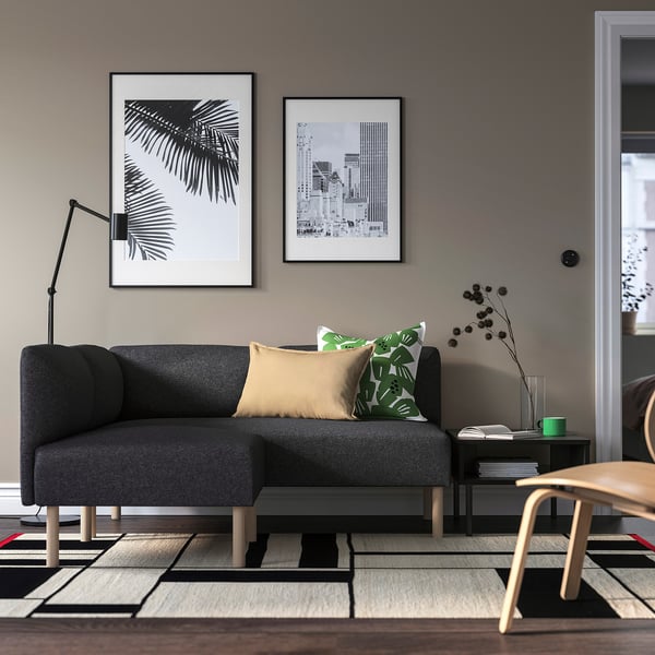 Modernes Wohnzimmer mit grauem LILLEHEM-Sofa, Kissen, Kunst, Lampe und gemustertem Teppich.