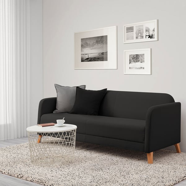 Modernes, minimalistisches Wohnzimmer mit schwarzem LINANÄS-Sofa, weißem Beistelltisch und Schwarz-Weiß-Dekor.
