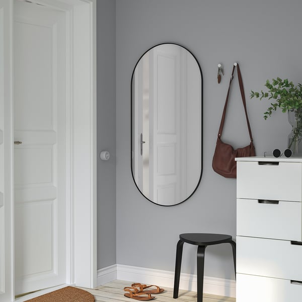 LINDBYN Spiegel an grauer Wandspiegeltür, größer als Kommode und Hocker.