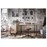 Arbeitsplatz im Industriestil mit Holzschreibtisch, grauem Hocker, Metallschränken und Wandkunst.
