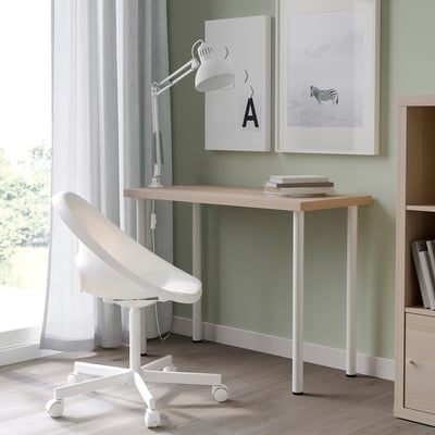 Home-Office-Einrichtung mit LINNMON-Tisch, weißem Stuhl, Lampe und Kunstwerk.