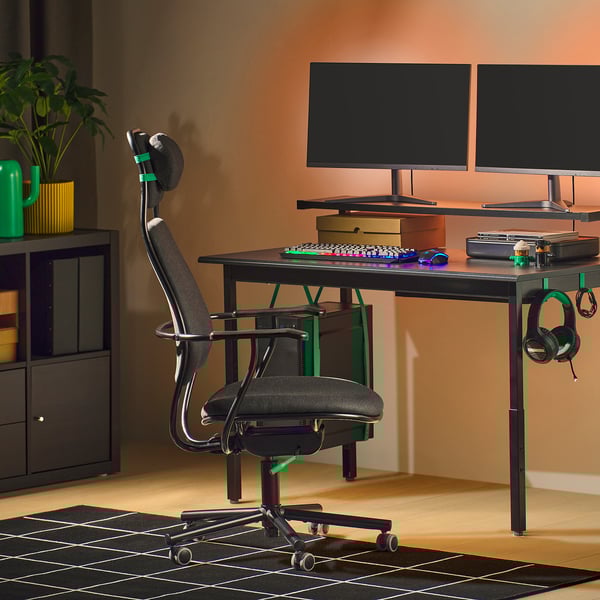 Modernes Gaming-Setup: schwarzer LÖPARBANA Stuhl, grüne Akzente, zwei Monitore, Tastatur, Maus auf dunklem Schreibtisch an der Wand.