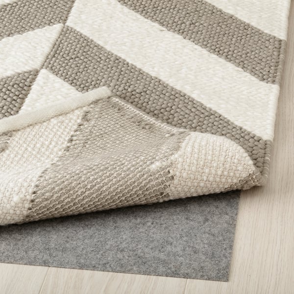 Geometrischer Wollteppich in Grau und Beige mit rutschfestem Polster.