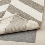 Geometrischer Wollteppich in Grau und Beige mit rutschfestem Polster.