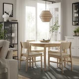 Modernes Esszimmer mit rundem Holztisch, vier Stühlen, stilvoller Leuchte, grauem Teppich und offener Tür, mit LUFTFARTYG-Teppich in neutralen Tönen.