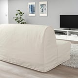 Modernes Wohnzimmer mit beigem Schlafsofa, TV-Schrank, Teppich, Pflanze, grauer Wandkunst.