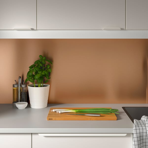 Moderne Küche mit LYSEKIL-Paneel. Die Theke besteht aus Frühlingszwiebeln, einem Messer, einer Pflanze und einer Schüssel.