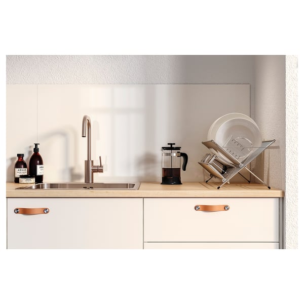 Moderne Küche mit hellen Schränken, einer Edelstahlspüle, einer Holzarbeitsplatte und verschiedenen Küchenaccessoires.