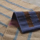 Gestreifte Decke aus strukturierter Wolle und Jute aus nächster Nähe, die komplizierte Webarten und erdige Farben zeigt.