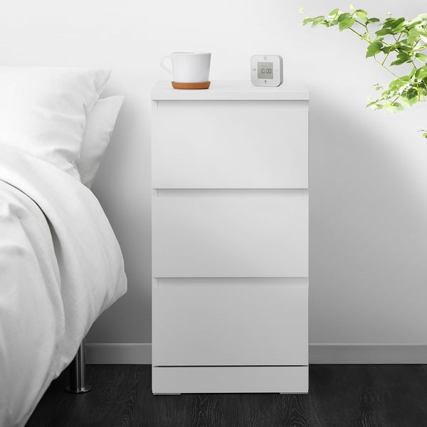 Weiße MALM-Kommode mit 3 Schubladen, Uhr und Tasse.