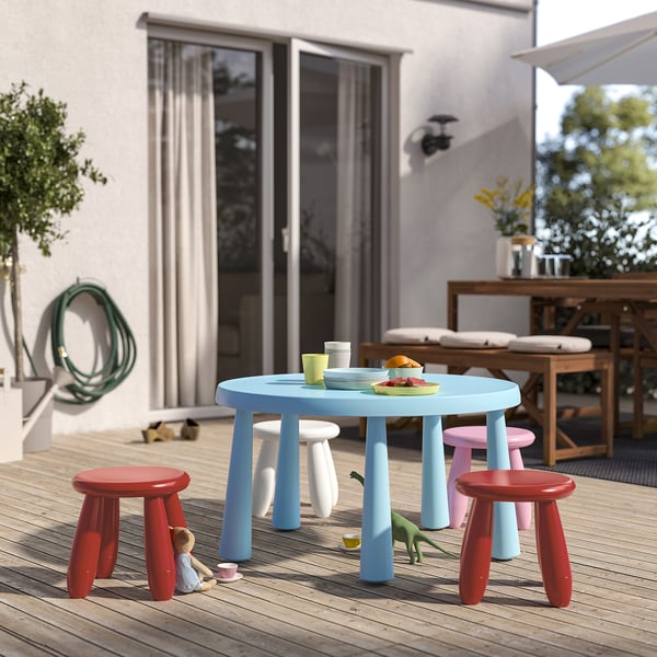 Blauer Kinderspieltisch mit 4 bunten Hockern, im Freien.