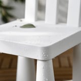 Weißer Kindertisch mit Wassertropfen, kleines grünes Blatt obendrauf.