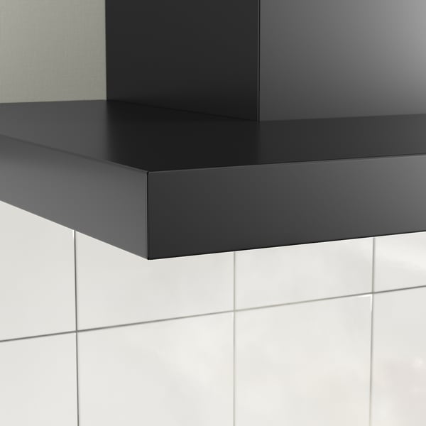 Schwarze moderne Dunstabzugshaube mit schlanken Linien und LED-Beleuchtung, die an einer gefliesten Wand montiert ist.