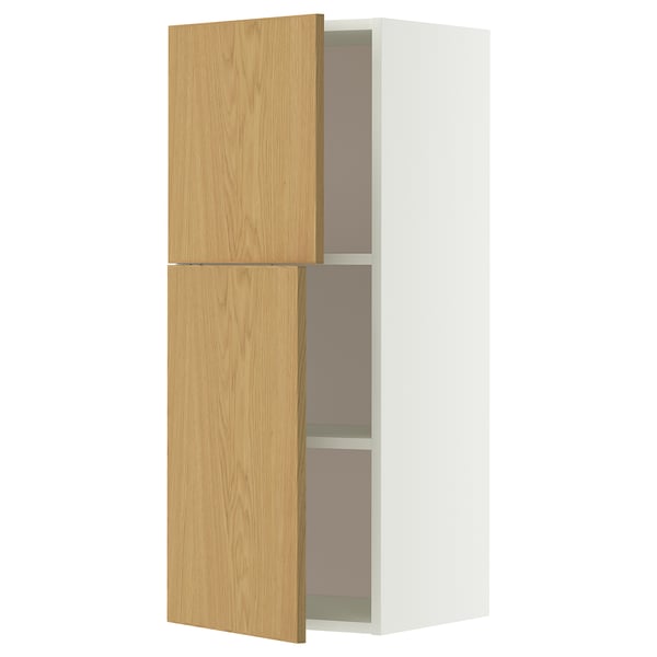 Ein METOD-Wandschrank in Weiß und Eiche mit zwei offenen Holztüren, die den Blick auf rosafarbene Innenregale freigeben.