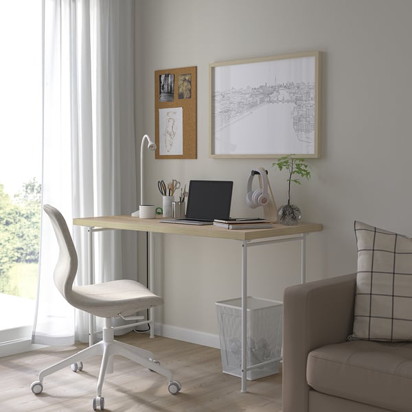 Minimalistisches Home Office mit weißem Schreibtisch, grauem Stuhl und Dekor.