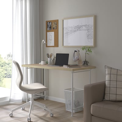 Minimalistisches Home Office mit weißem Schreibtisch, grauem Stuhl und Dekor.
