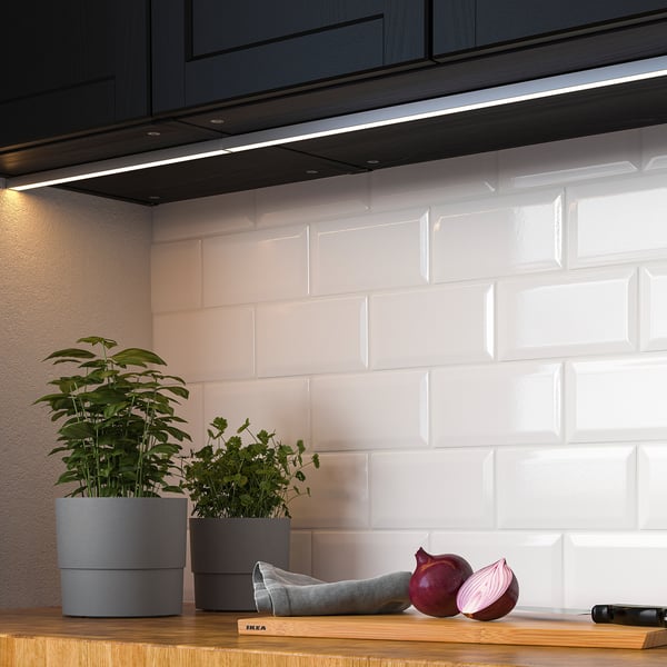 Moderne Küche mit LED-Beleuchtung unter dem Schrank, Pflanzen und Zwiebeln auf einer Holztheke.