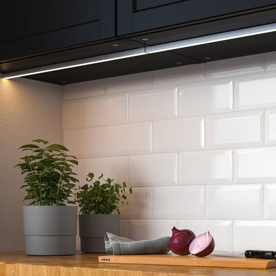 Moderne Küchentheke mit integrierten LED-Leuchten, Pflanzen und Zwiebeln. Die Leuchten verbessern die Effizienz und das Ambiente der Arbeit.