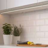 Moderne Küche mit Unterschrankbeleuchtung, Pflanzen, Zitrone und Messer auf der Theke.