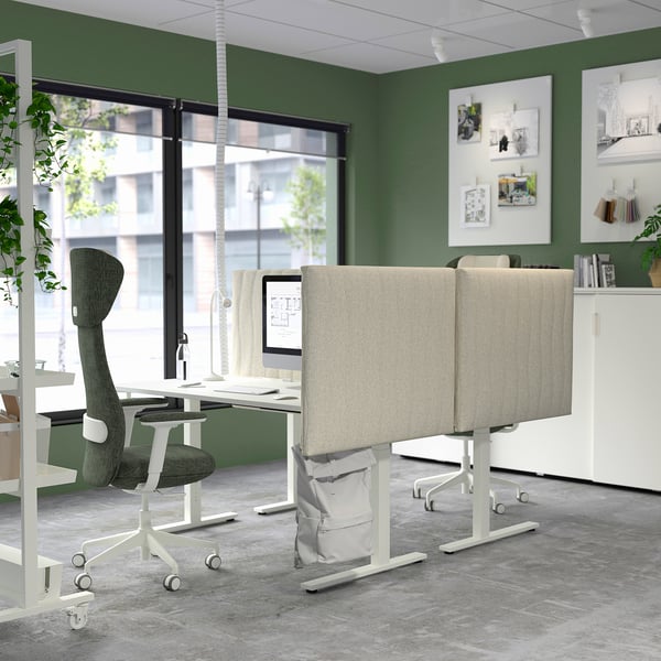 Modernes Büro mit beigen MITTZON-Akustikschirmen, grauem Stoff, Trennwänden auf den Schreibtischen, grünen Wänden, großen Fenstern, Pflanzen und modernem Dekor.