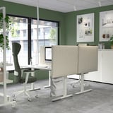 Modernes Büro mit beigen MITTZON-Akustikschirmen, grauem Stoff, Trennwänden auf den Schreibtischen, grünen Wänden, großen Fenstern, Pflanzen und modernem Dekor.