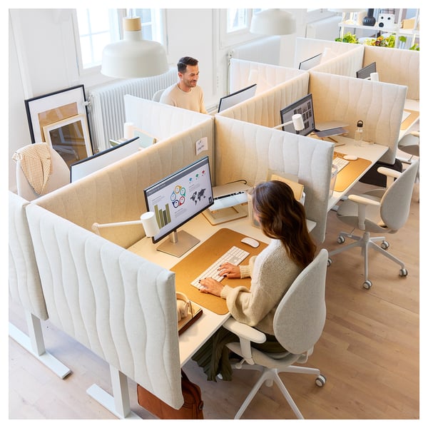 Modernes Büro mit Mitzon-Schreibtischen, beigen Stoffschirmen, Computern, Stühlen. Zwei Arbeiter arbeiten in einem hellen, ruhigen Raum zusammen.