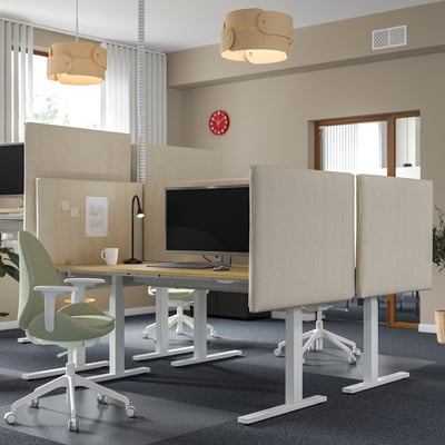 Modernes Büro mit MITTZON Stehpulten, grünen Stühlen, beigen Trennwänden, roter Uhr, Holzlampen. Die Schreibtische sind größer und mittig platziert.