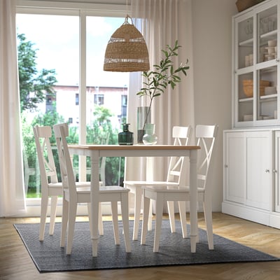 Esszimmer mit MORUM-Teppich, Tisch, Stühlen und großen Fenstern. Zur Einrichtung gehören Vasen und Grünzeug. Die Teppichverankerung ermöglicht eine einfache Bewegung des Stuhls.