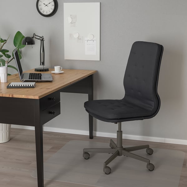 Einrichtung des Home-Office: schwarzer MULLFJÄLLET-Stuhl, Schreibtisch aus Holz, Laptop, Lampe, Pflanze und Wandkunst.