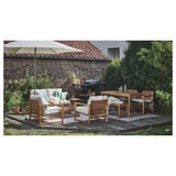 Gartenmöbel für den Außenbereich mit Holztisch, Stühlen und Sofa unter einem beigen Sonnenschirm, angeordnet auf einer Holzterrasse in der Nähe eines Backsteinhauses.