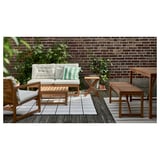 Nammaro Terrassengarnitur: Sofa, Stühle, Tische mit Kissen, Ziegelwand, Pflanzen.