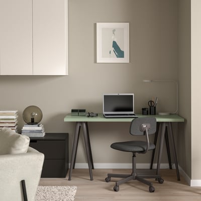 Minimalistisches Homeoffice: schwarzer NÄRSPEL Schreibtisch mit grüner Platte, grauem Stuhl, Kunstwerk und Buchaufsteller.
