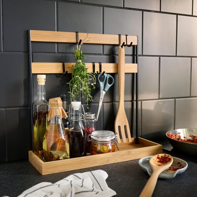 Ein NÅLBLECKA Bambus Küchenorganizer mit schwarzen Metallhaken und Regalen, ideal zur Aufbewahrung von Küchenutensilien und Gewürzen.