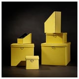 Sechs knallgelbe, stapelbare Aufbewahrungsboxen in verschiedenen Größen, mit Deckeln und Metallgriffen, ordentlich angeordnet vor dunklem Hintergrund.