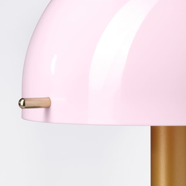 Eine Nahaufnahme einer rosa Lampe mit goldenem Scharnier, die ihr schlankes, modernes Design und ihre hochwertigen Materialien zur Geltung bringt.