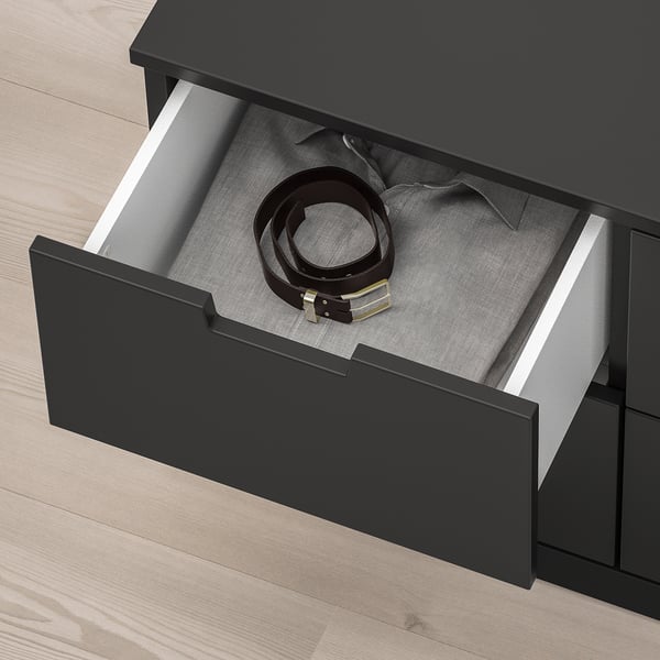 Die schwarze NORDLI-Schublade lässt sich öffnen und gibt den Blick auf einen Gürtel im Inneren frei. Die Schublade verfügt über einen Soft-Close-Mechanismus.