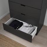 Schwarze Kommode mit einer offenen Schublade, die den Blick auf ordentlich gefaltete Kleidung freigibt. Die Schublade verfügt über einen Soft-Close-Mechanismus.