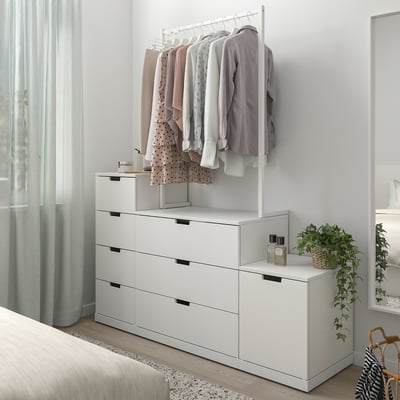 NORDLI weiße Kommode, schlank und modern, mit Kleiderstange. Hängt in der Nähe des Bettes, passt gut ins Zimmer.