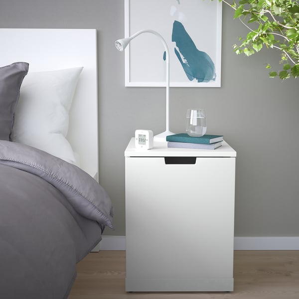 Modernes Schlafzimmer mit NORDLI Truhe, Lampe, Büchern und Kunst.