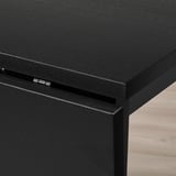 Schwarze Tischecke aus Holz mit Metallscharnier, die sich durch eine robuste Konstruktion und eine schlanke Verarbeitung auszeichnet.